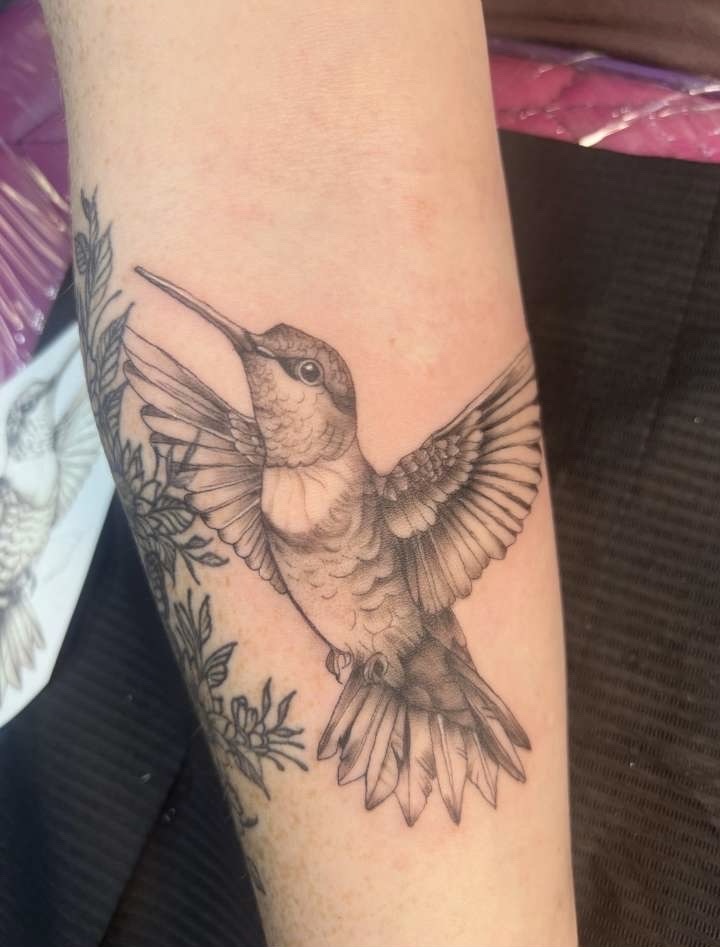 Fine line black and grey hummingbird with botanicals forearm tattoo