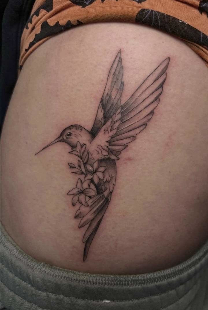 Black and grey hummingbird with blossoms hip tattoo