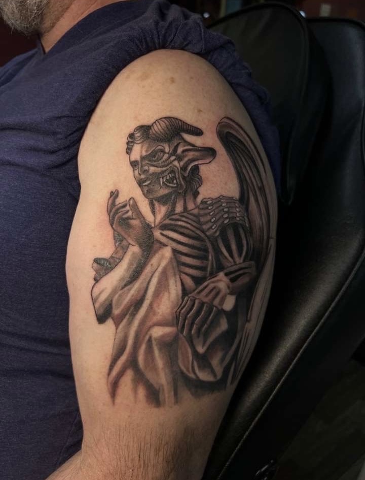 Black and grey winged demon figure upper arm tattoo