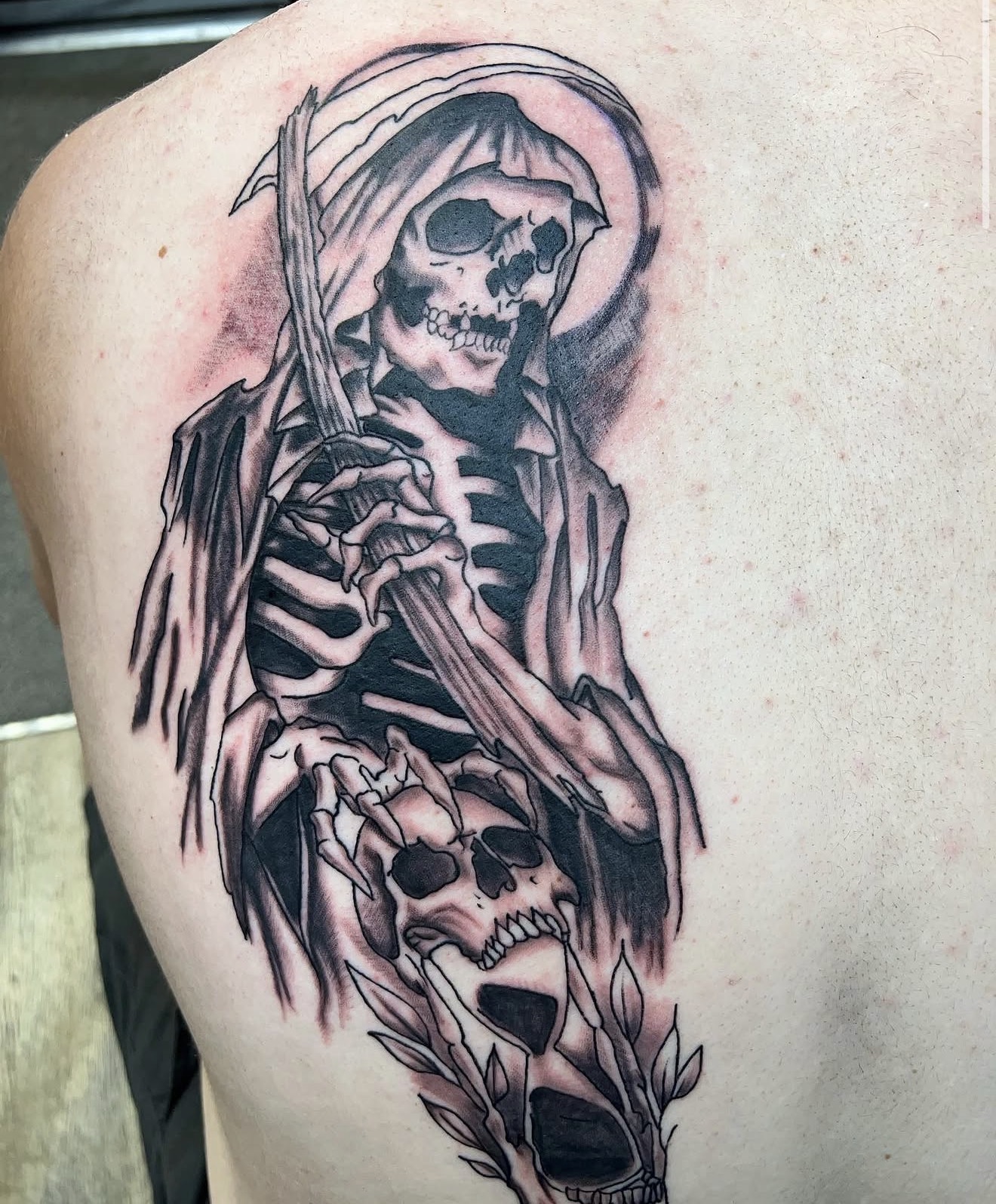 Black and grey grim reaper with scythe and skull back tattoo