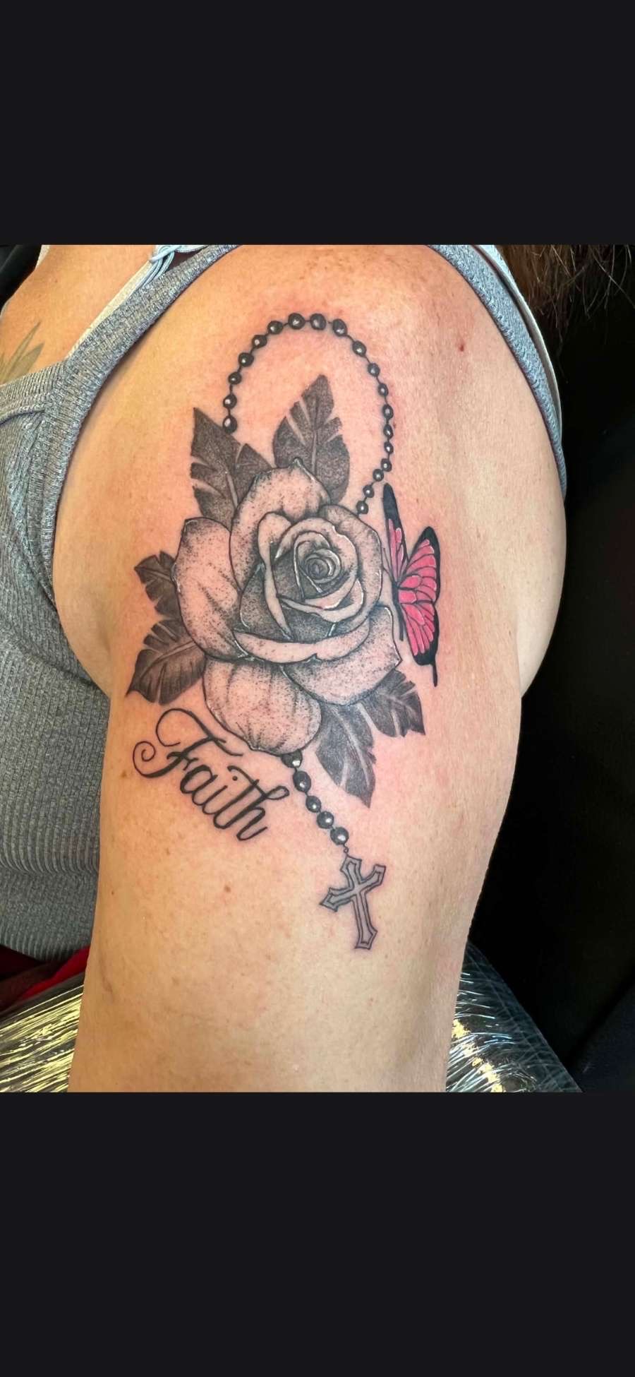 Black and grey rose with rosary, pink butterfly and Faith script arm tattoo