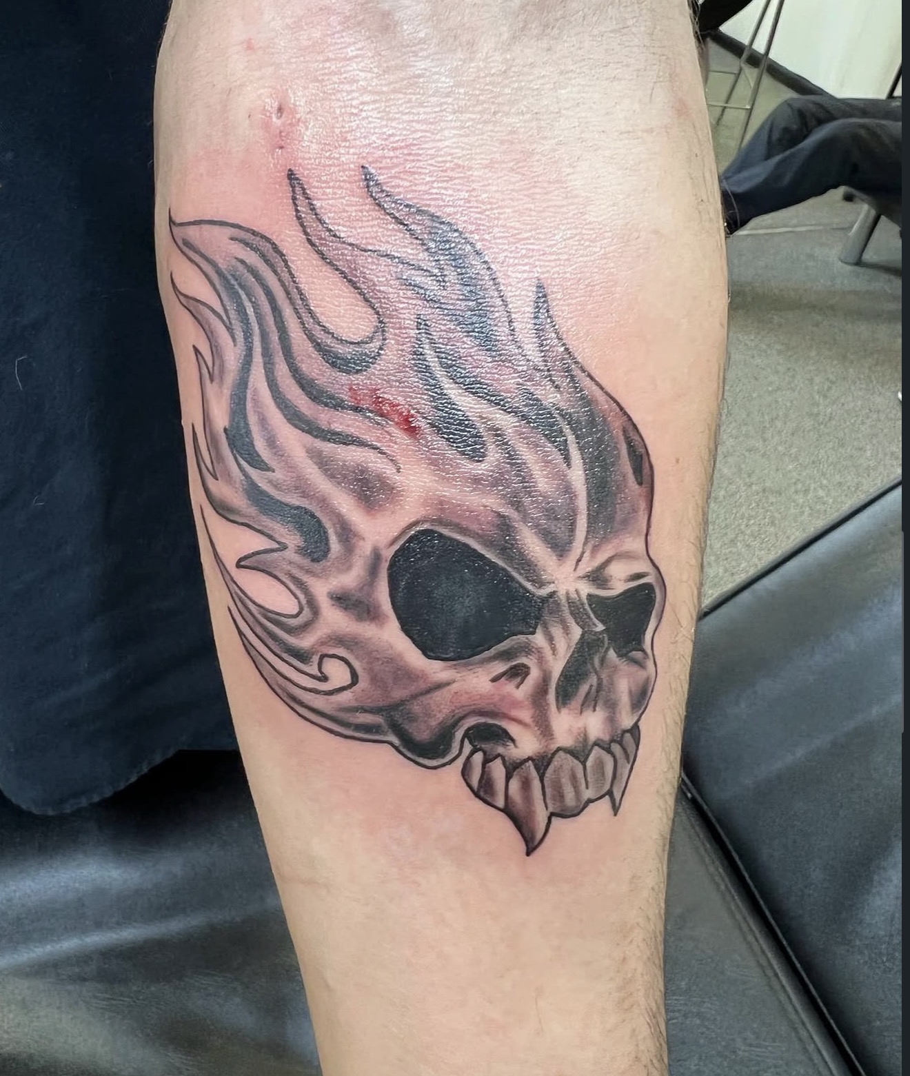 Black and grey flaming fanged skull calf tattoo